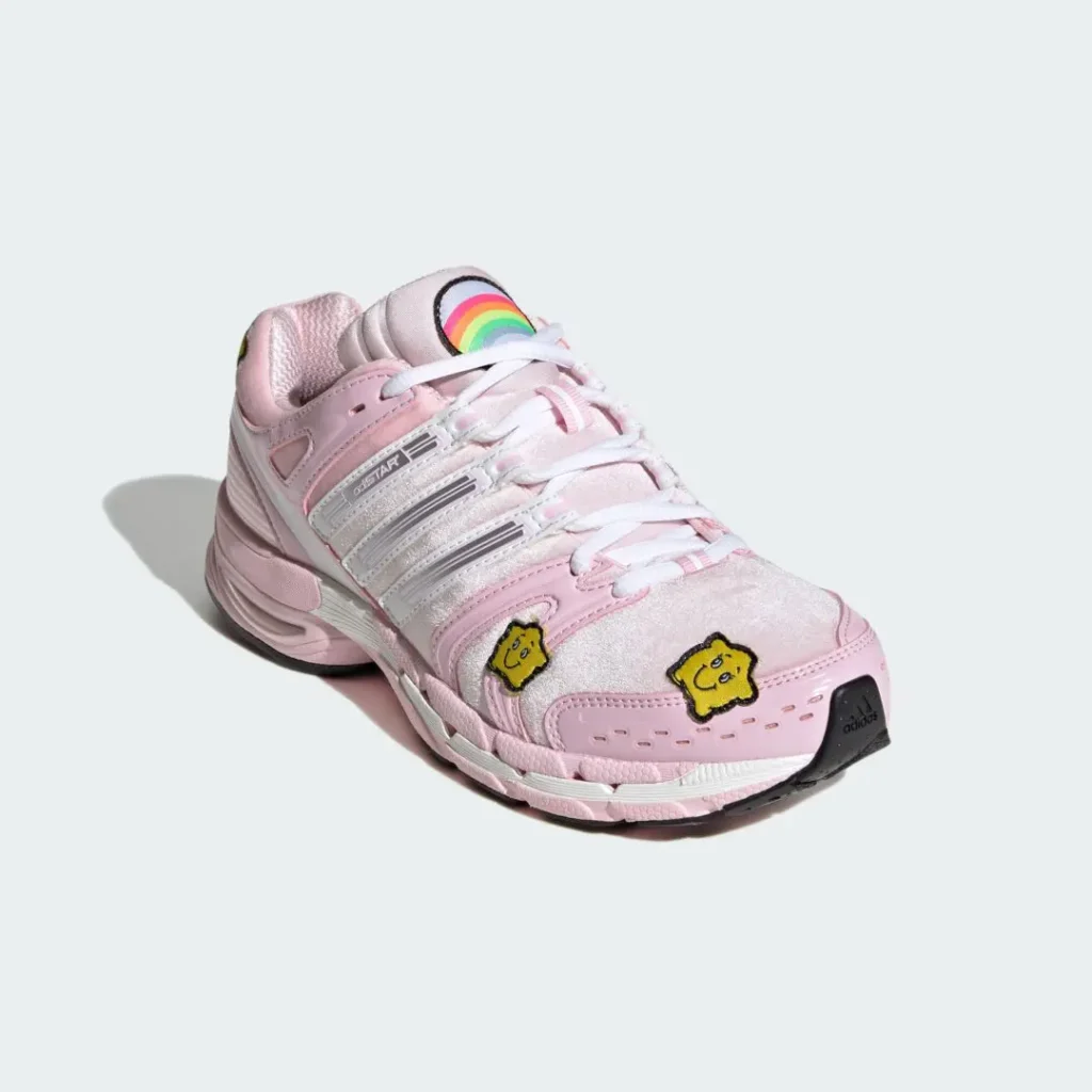 Pink Adidas shoe with white stripes, rainbow tongue logo, and two yellow smiling star patches on the toe box