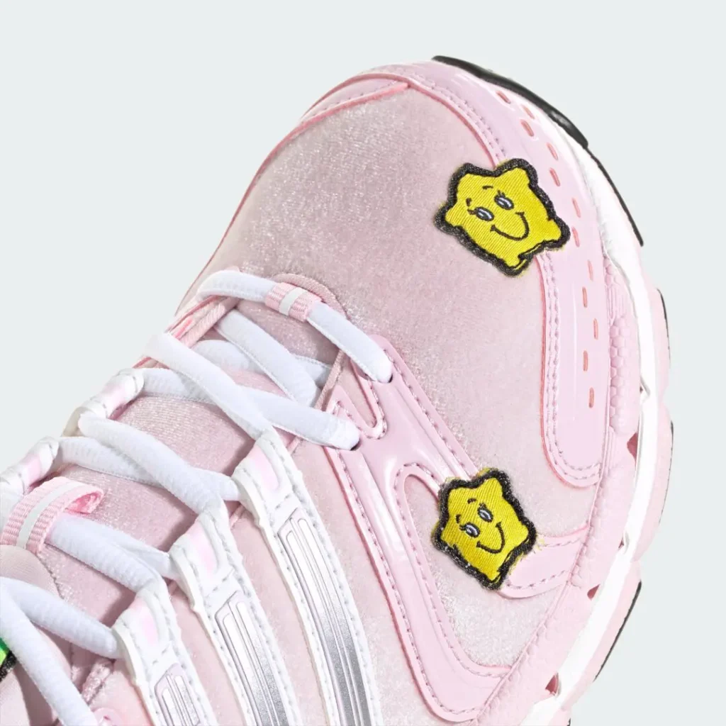 Close-up of a pink sneaker with white laces, silver accents, and two yellow smiling star patches