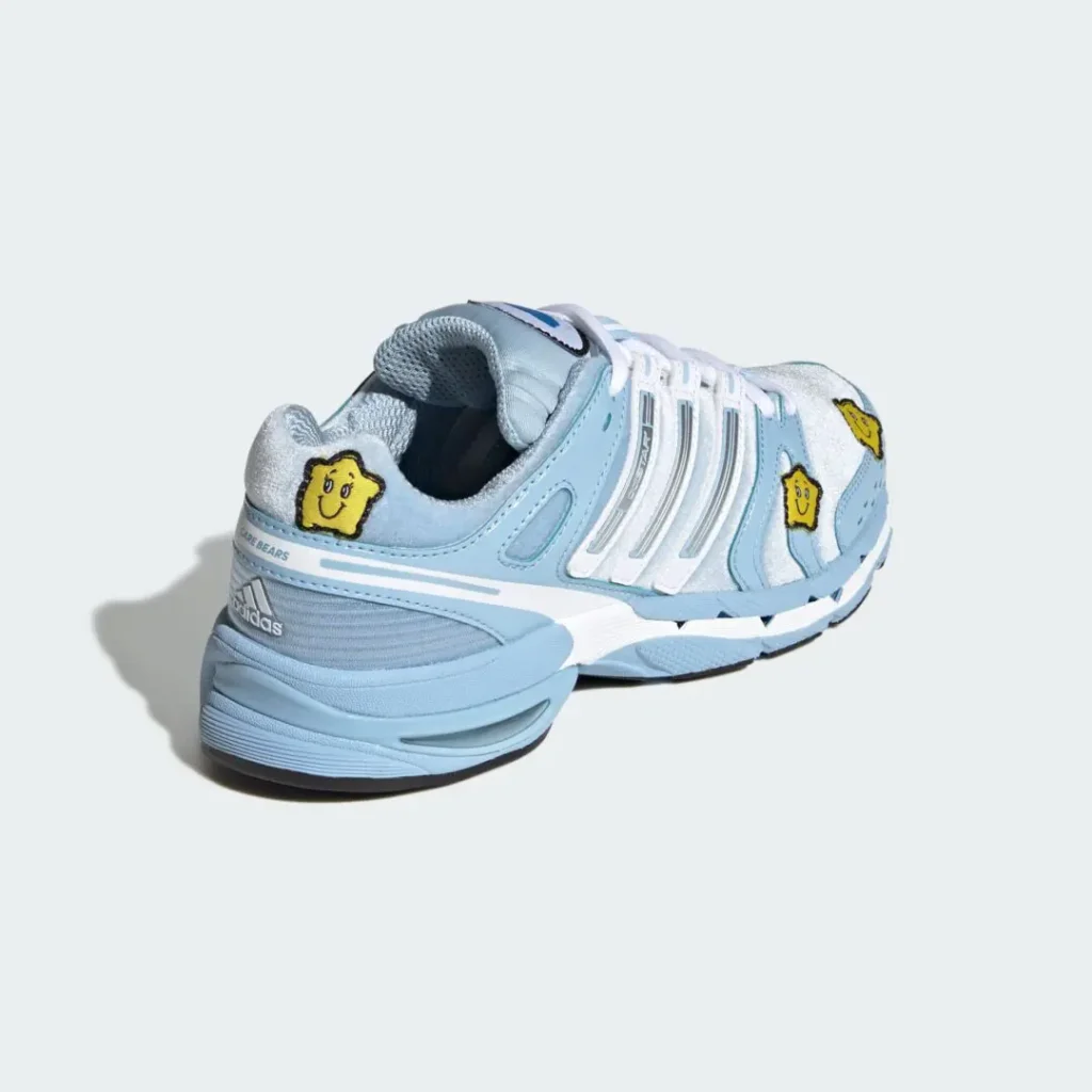 Light blue and silver Adidas sneakers with white stripes and yellow smiling star patches on a pale background