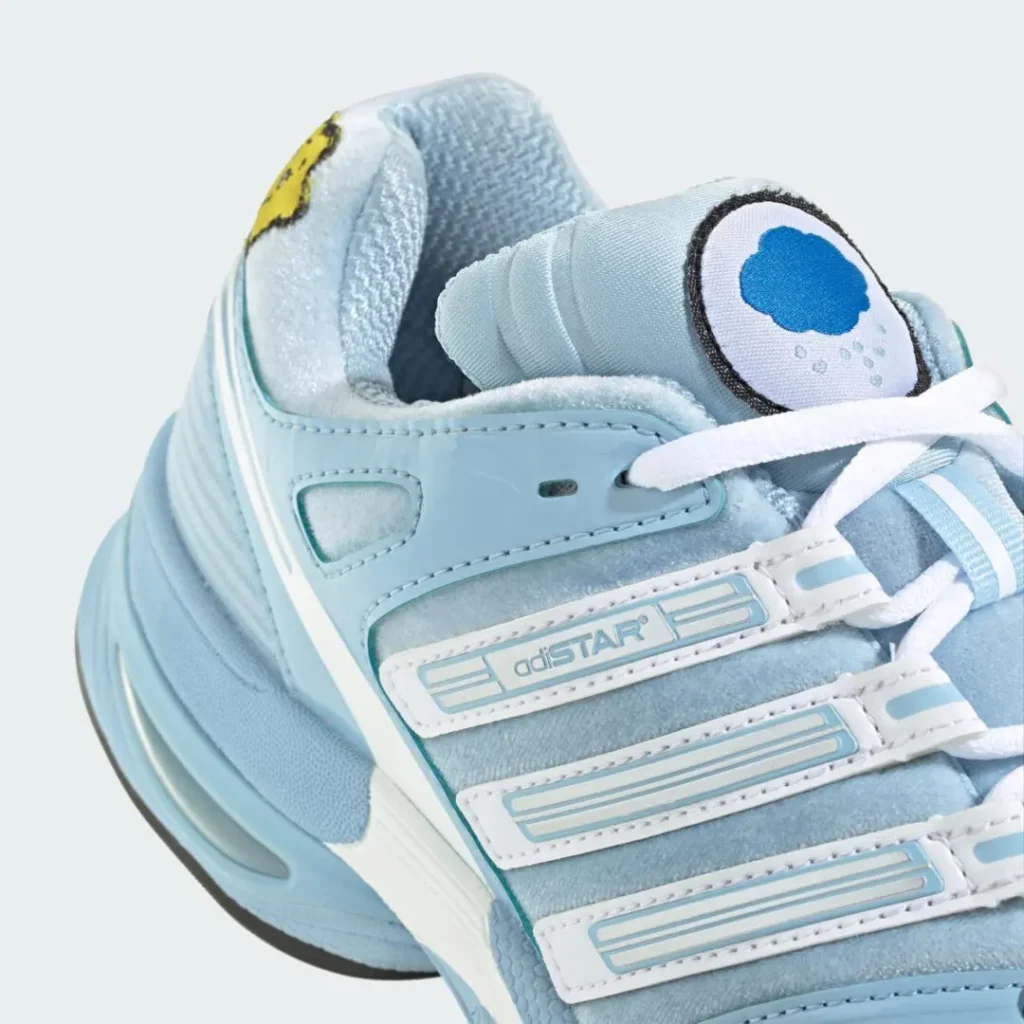 Close-up of a pale blue and white Adidas high-top sneaker with layered straps, white laces and a cloud tongue emblem