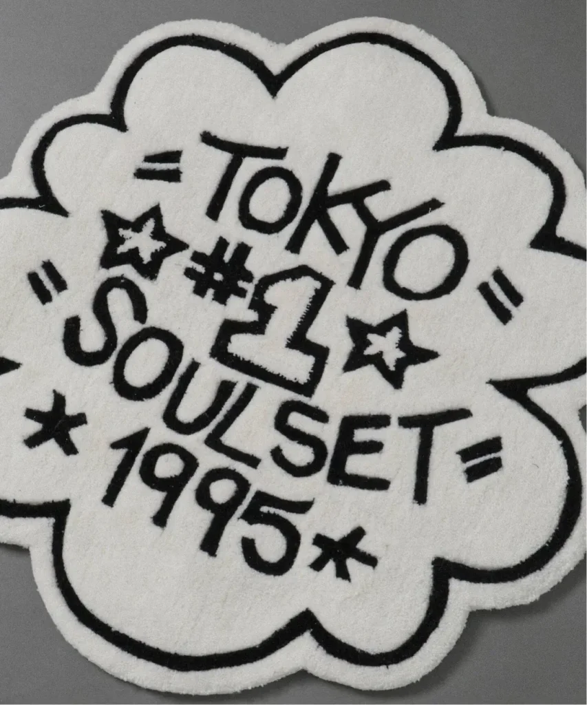White flower-shaped patch with black outline, “TOKYO SOULSET 1996” lettering and star motifs on a gray background