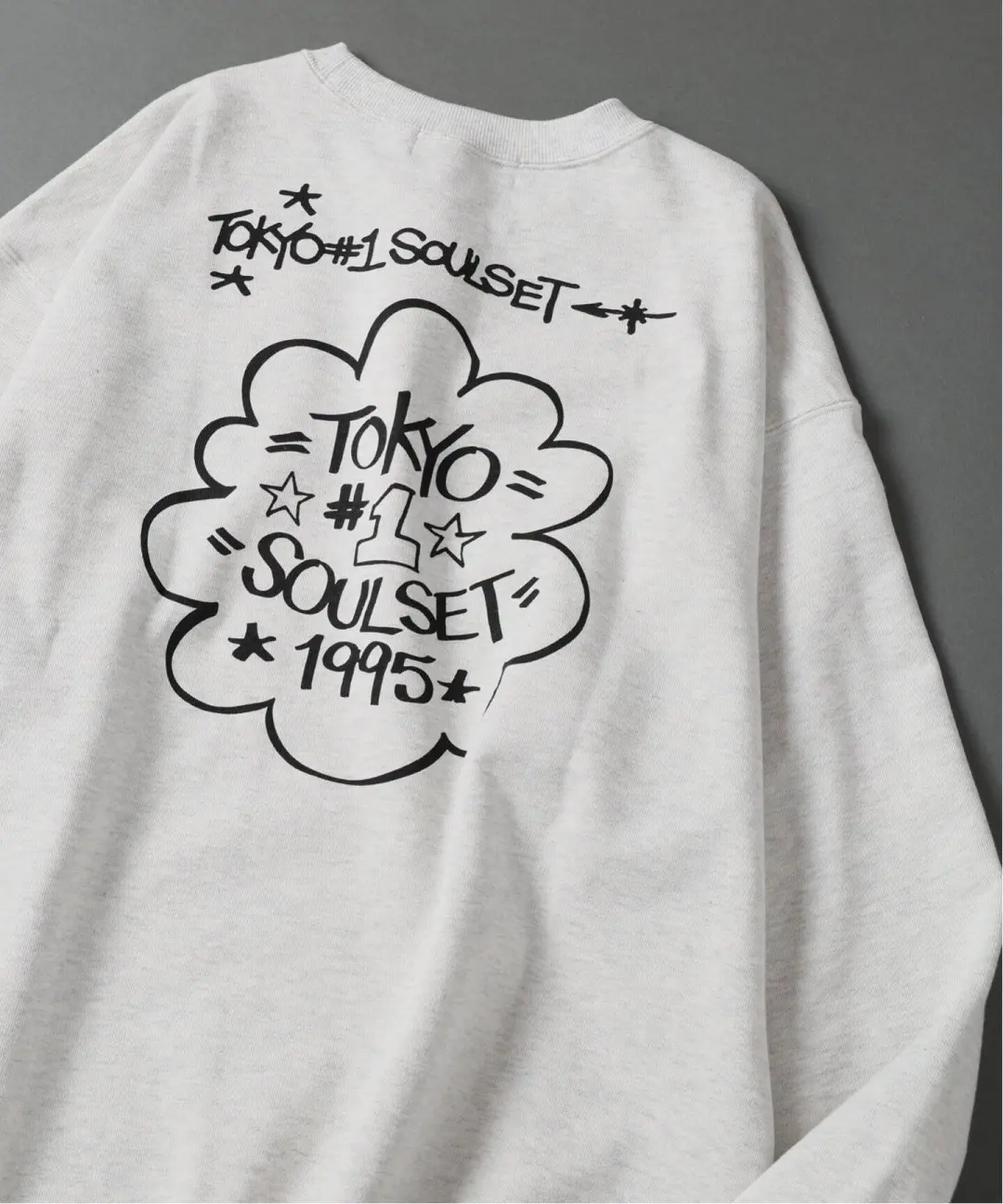 White sweatshirt with black Tokyo Soulset 1975 graphic and lettering laid flat on a gray background