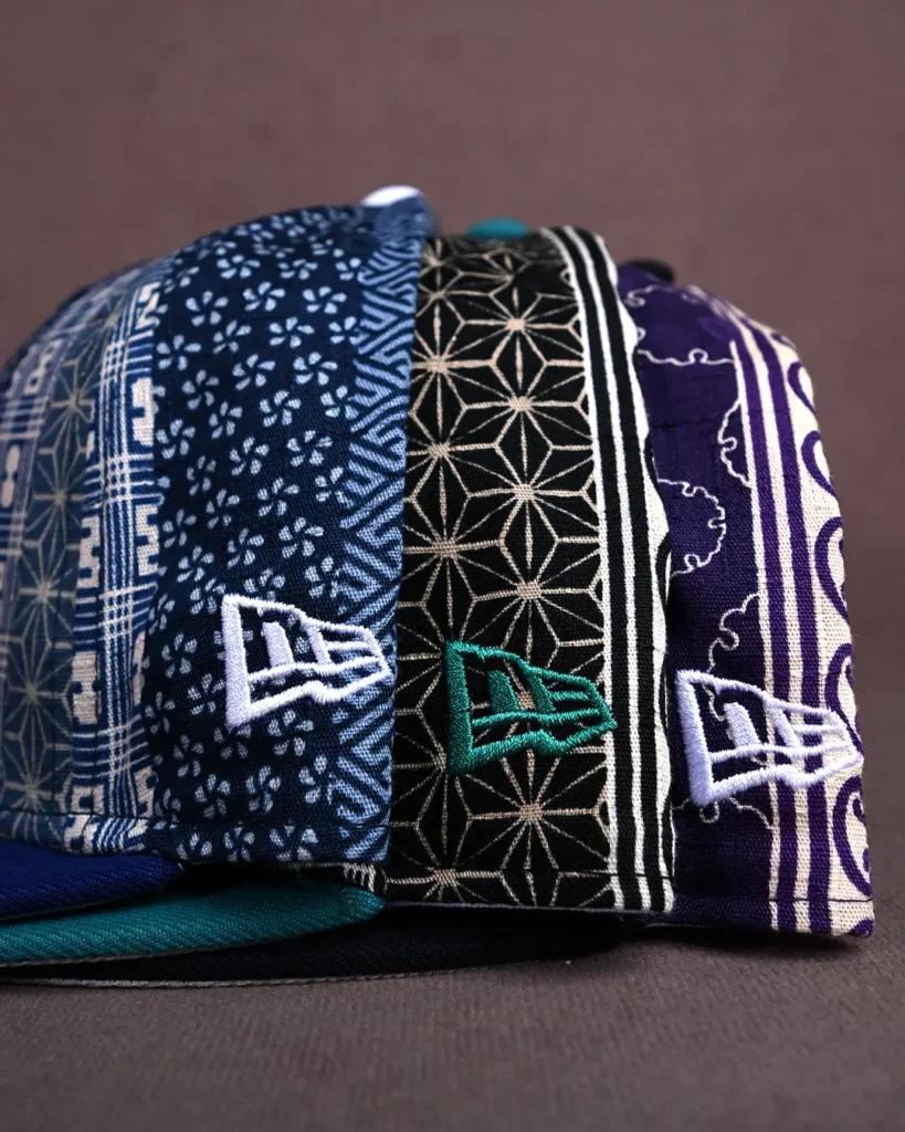 Stacked patterned fabric caps in navy, black, purple, teal and white, displayed on a dark tabletop