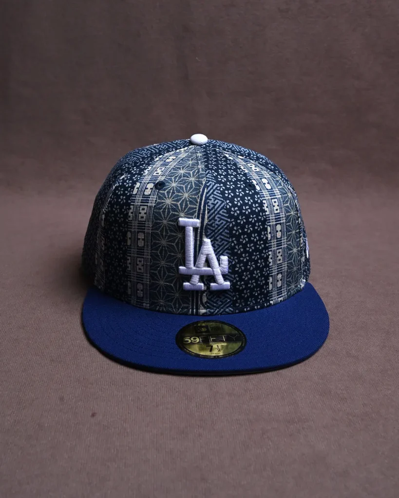 Blue patterned Los Angeles Dodgers baseball cap with a flat brim and white “LA” logo on a brown surface