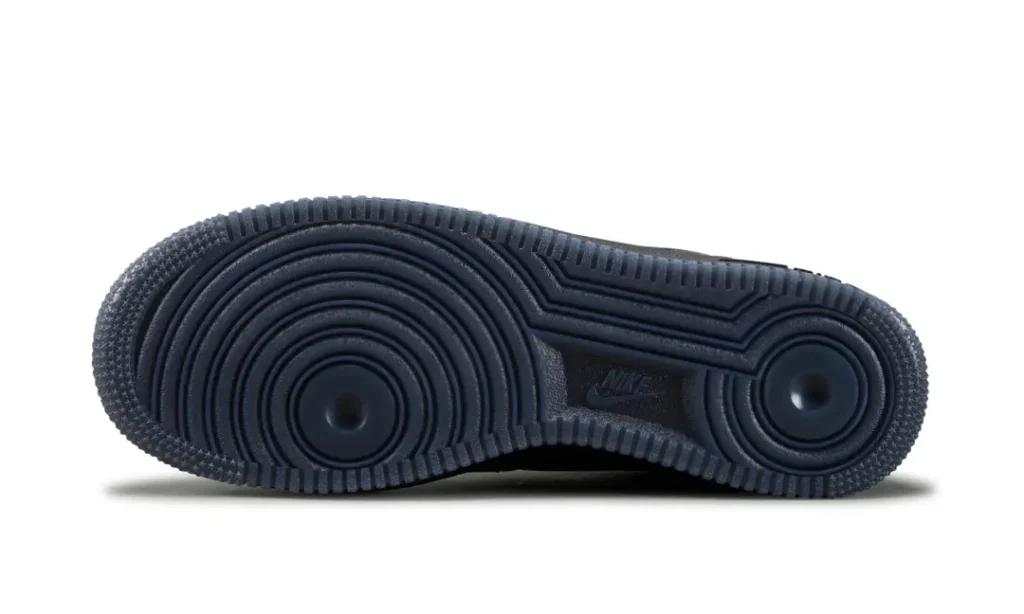 Black Nike sneaker outsole with concentric circular tread and textured edges, shown side-on against a white background
