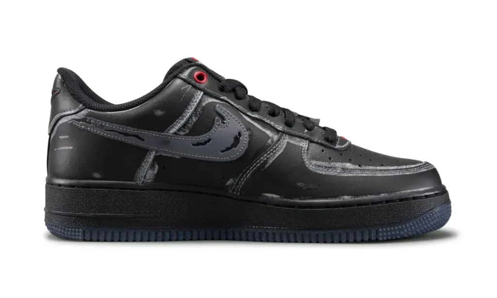 Black low-top shoe with stitched panels, side swoosh, black laces, red eyelet, and textured rubber sole on white