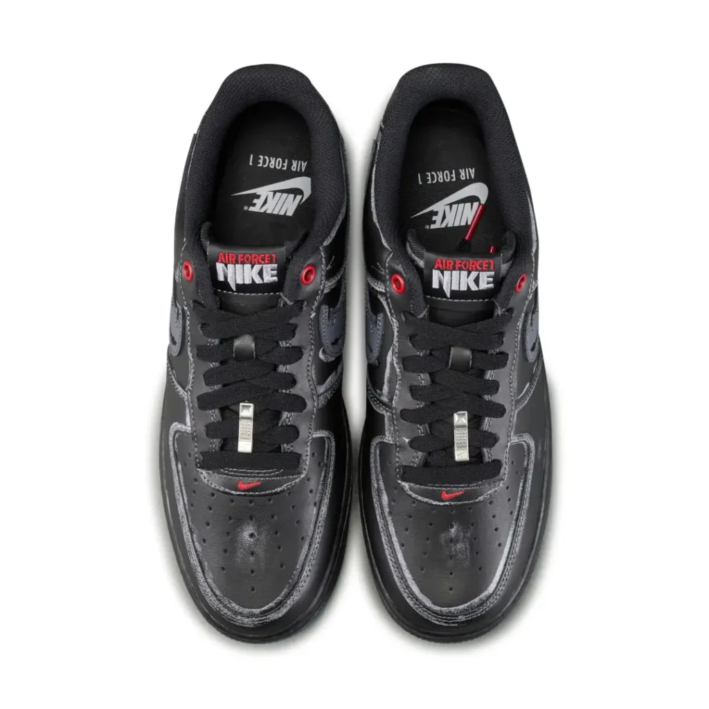 Pair of black Nike Air Force 1 sneakers with red accents, viewed from above on a white background