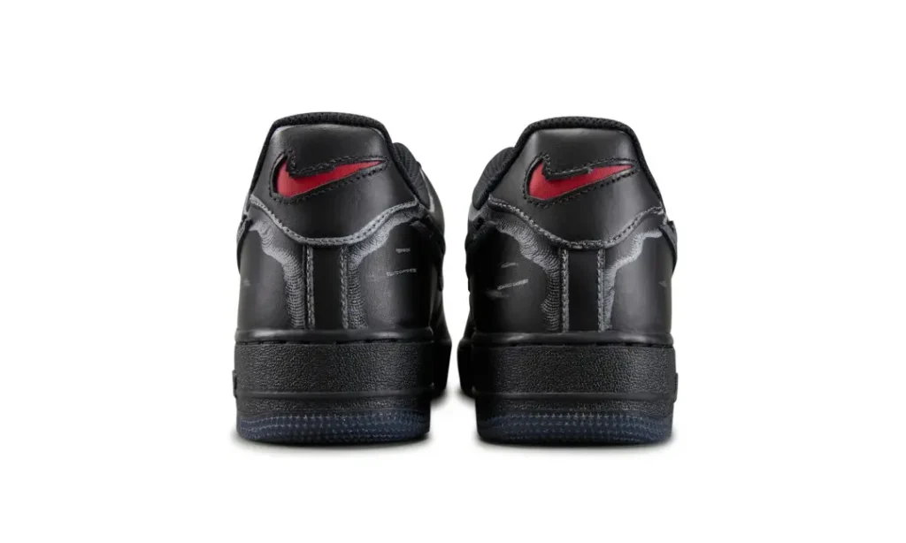 Rear view of black Nike sneakers with red swooshes, positioned side by side against a white background