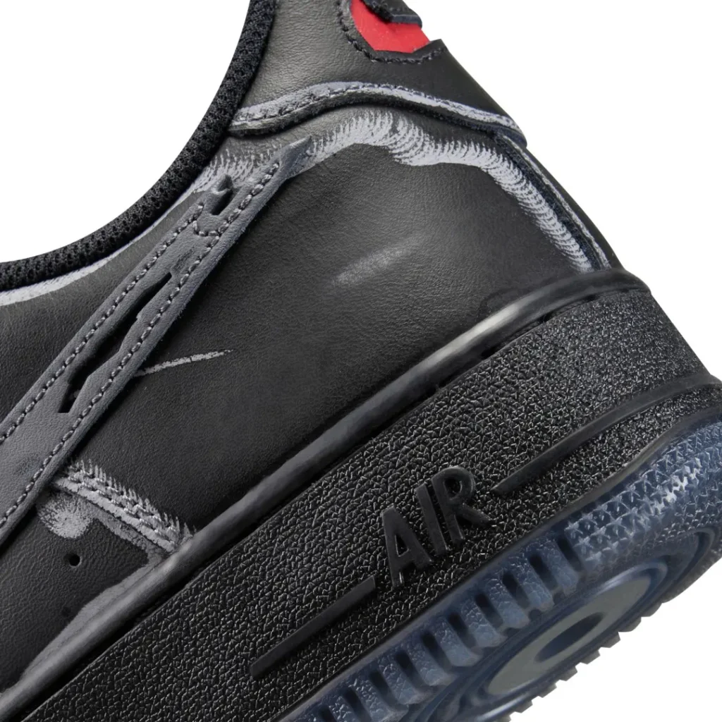 Close-up of a black leather sneaker with gray stitching, red collar detail, raised AIR lettering, and translucent blue sole