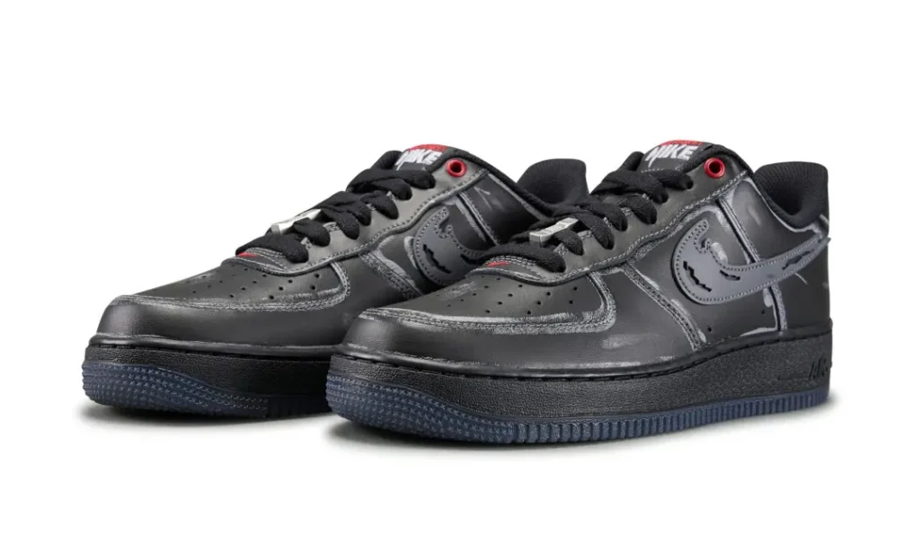 Pair of black Nike low-top sneakers with swoosh logos, red eyelets, and textured dark soles on a white background