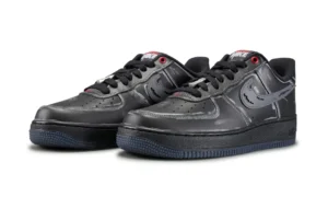 Pair of black Nike low-top sneakers with swoosh logos, red eyelets, and textured dark soles on a white background