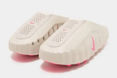 Pair of off-white slide sandals with perforated footbeds, scalloped soles, and bright pink accents on a white background