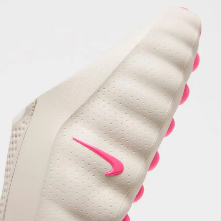 Close-up of a white shoe sole with perforations and bright pink tread accents