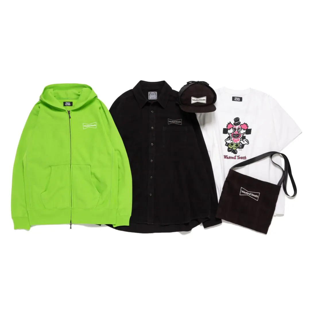 Green zip hoodie, black shirt and cap, white graphic T-shirt, and black shoulder bag arranged on a white background