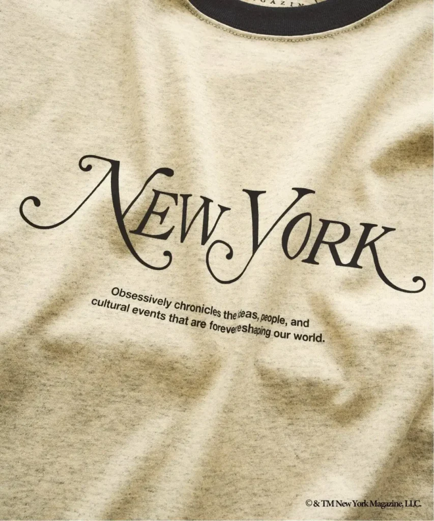 Close-up of a beige T-shirt featuring large black New York lettering and smaller descriptive text