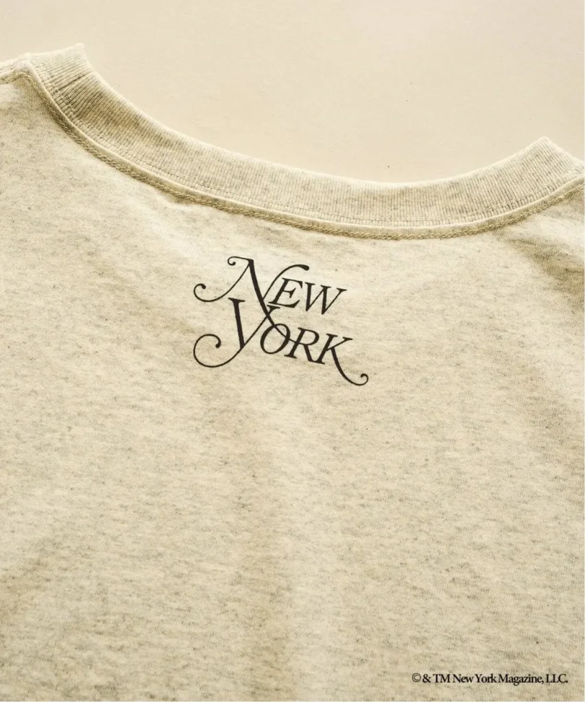 Close-up of a cream T-shirt with a ribbed neckline and black New York logo text on the chest