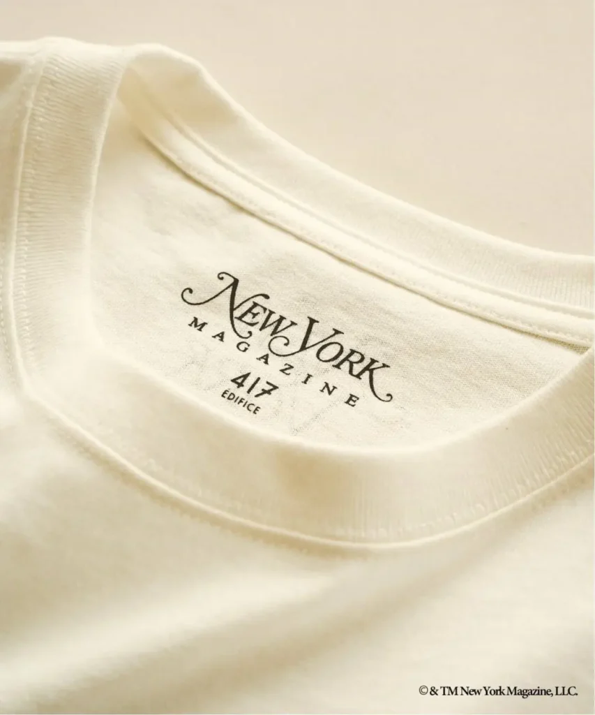Close-up of a cream T-shirt neckline with New York Magazine 4/7 Edition logo printed in black