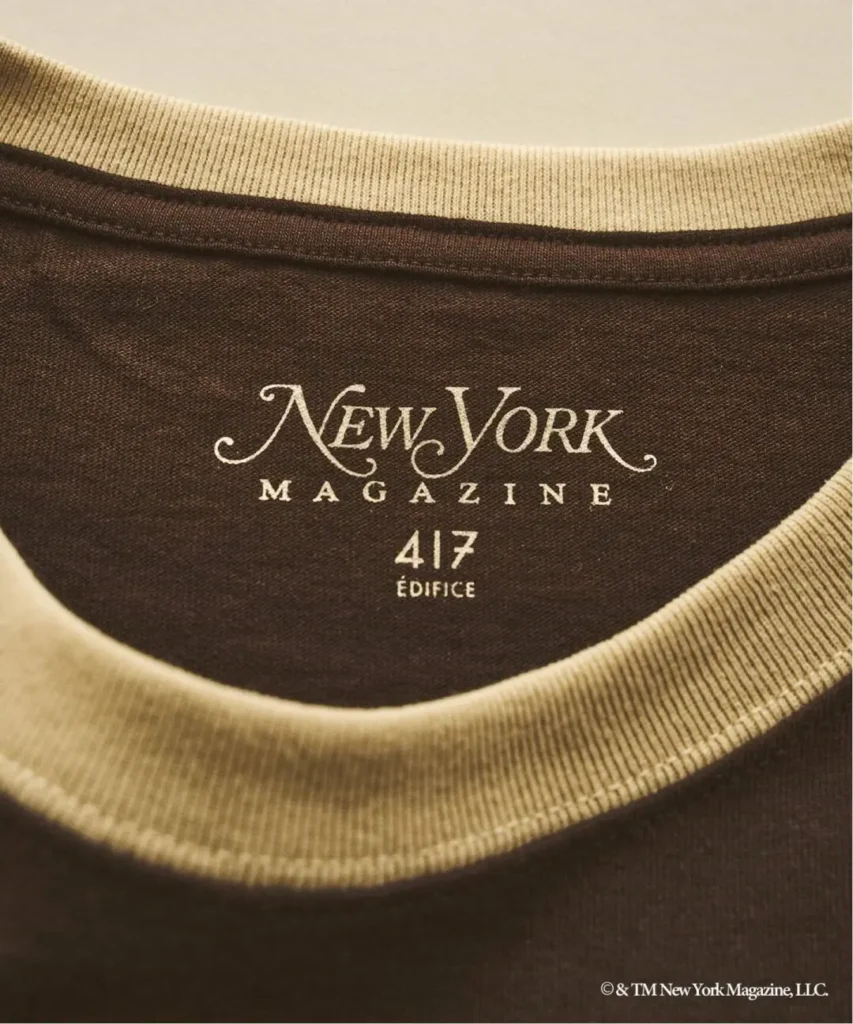 Close-up of a brown shirt with cream ribbed collar and cuffs, printed “New York Magazine 417 Edifice” logo
