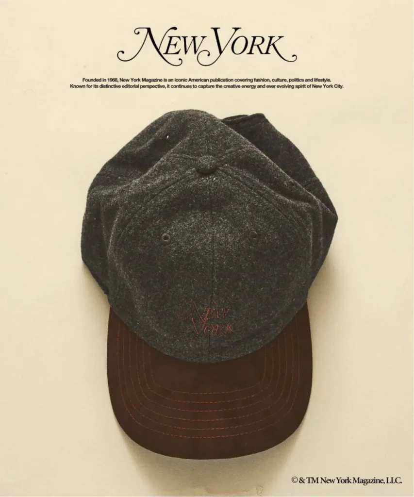 Dark gray wool cap with brown brim and red stitching, centered beneath the New York logo on a cream background