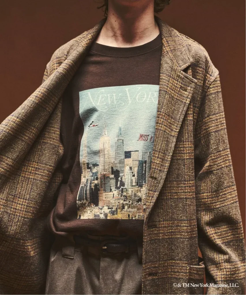 Person wearing a plaid blazer over a New York City graphic T-shirt and high-waisted trousers