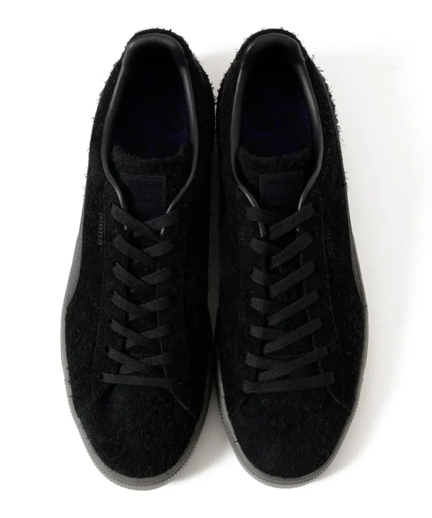 Pair of black fuzzy-textured lace-up sneakers with gray soles, viewed from above on a white background