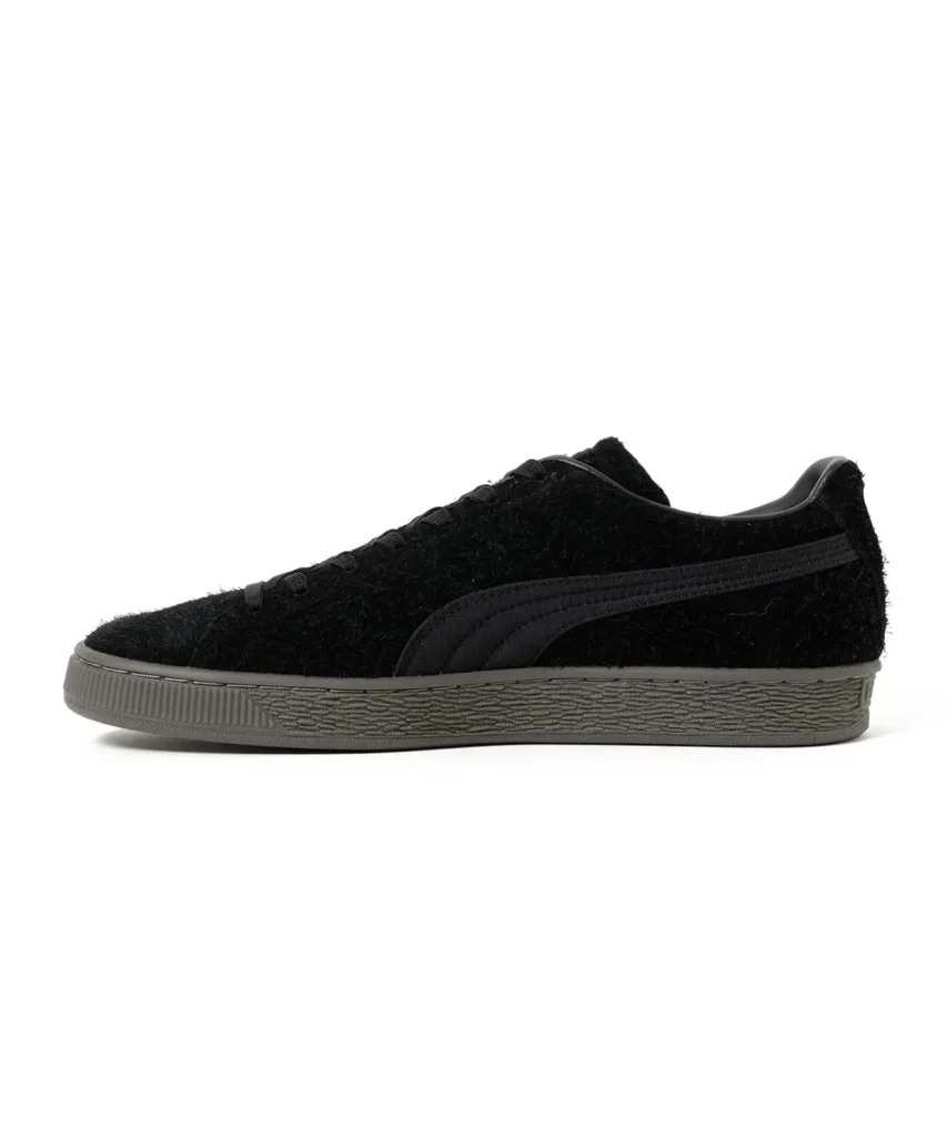 Black low-top sneaker with fuzzy upper, black side stripe, and textured gray rubber sole on a white background