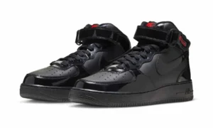 Pair of black patent Nike Air Force 1 Mid sneakers with ankle straps, black swooshes and red branding on a white background
