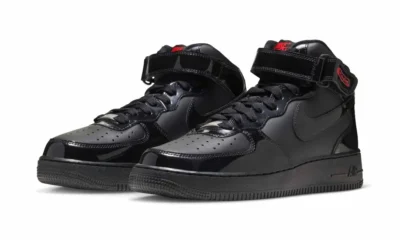 Pair of black patent Nike Air Force 1 Mid sneakers with ankle straps, black swooshes and red branding on a white background