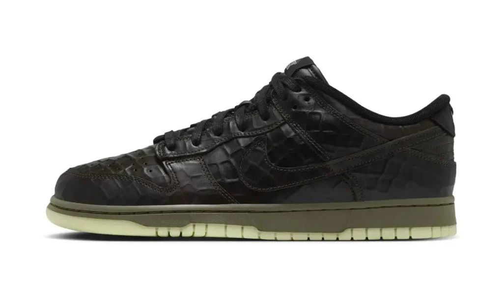 Black low-top Nike sneaker with embossed crocodile texture and a pale glow-in-the-dark sole on white background
