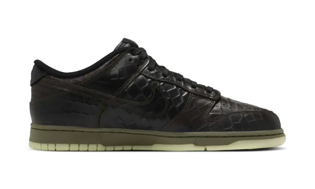 Black low-top sneaker with textured leather panels, black swoosh, olive midsole, and translucent pale green outsole on white