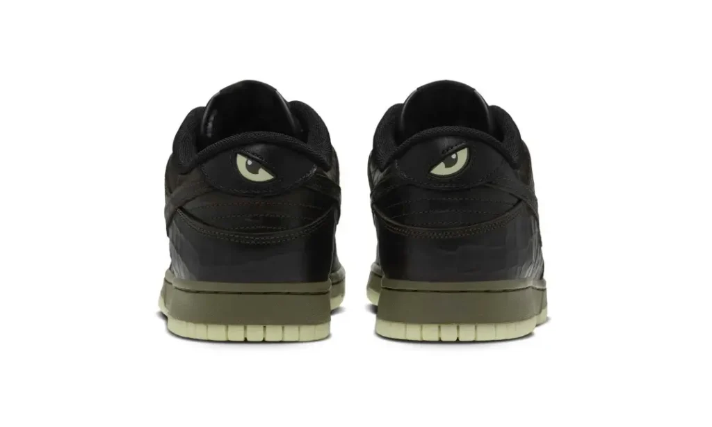 Pair of black sneakers shown from the rear, featuring stylized eye details and olive-green soles on a white background