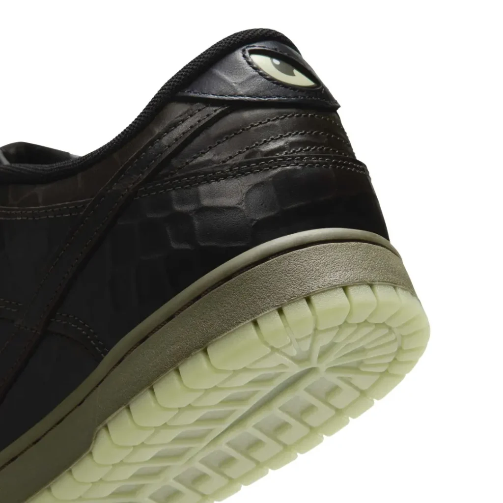 Close-up of a black leather sneaker heel with stitched panels, an eye graphic, and a translucent pale green textured sole