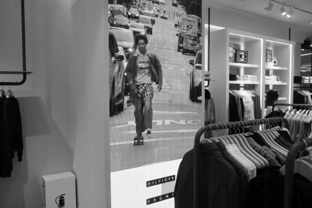 Clothing store with racks of garments and a large screen showing a skateboarder in a city street