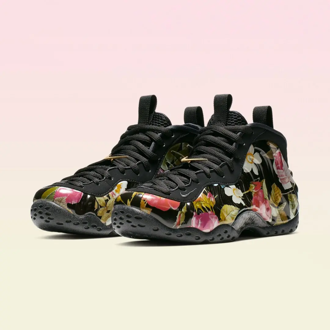 Pair of black high-top sneakers with glossy floral-print shells, black laces, gold lace locks, and textured soles on a