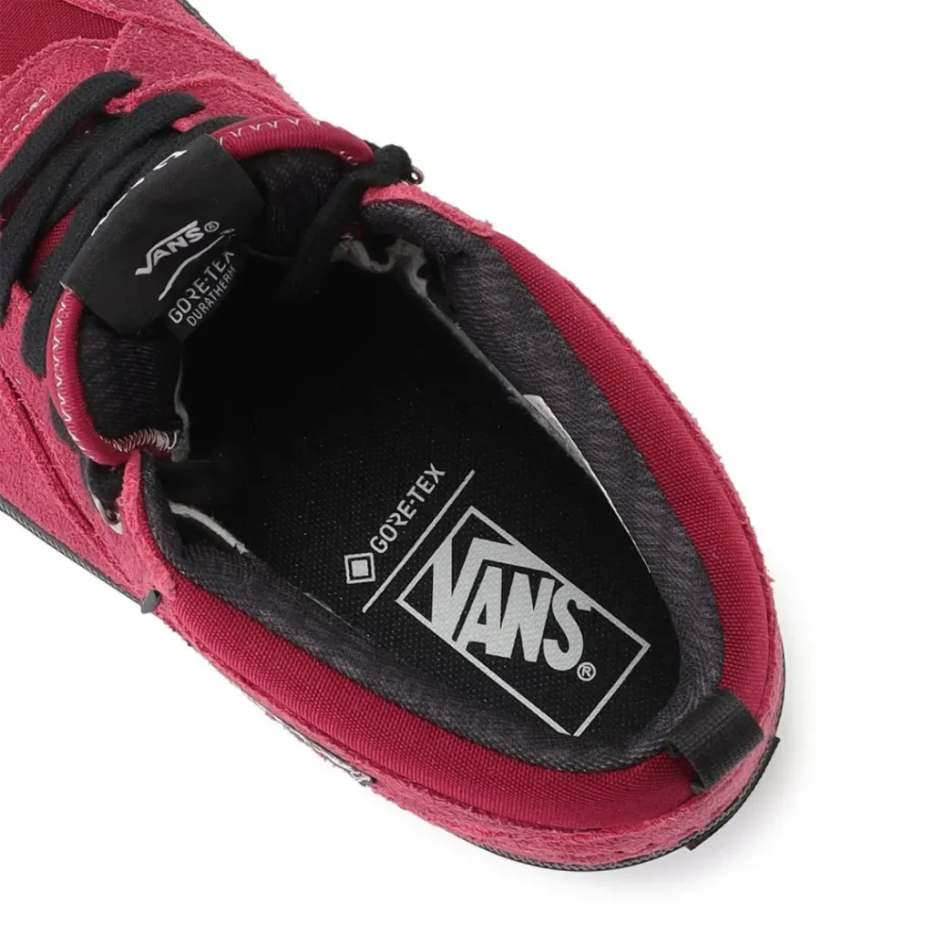 Close-up of a red Vans shoe with black laces, black lining, and Gore-Tex branding on a white background