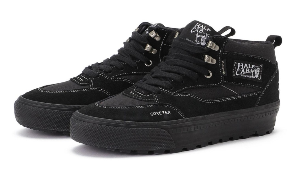Pair of black high-top sneakers with white stitching, metal lace hooks, Gore-Tex branding and lugged soles on a white