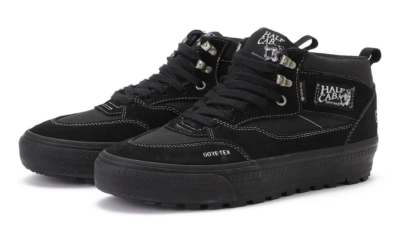 Pair of black high-top sneakers with white stitching, metal lace hooks, Gore-Tex branding and lugged soles on a white
