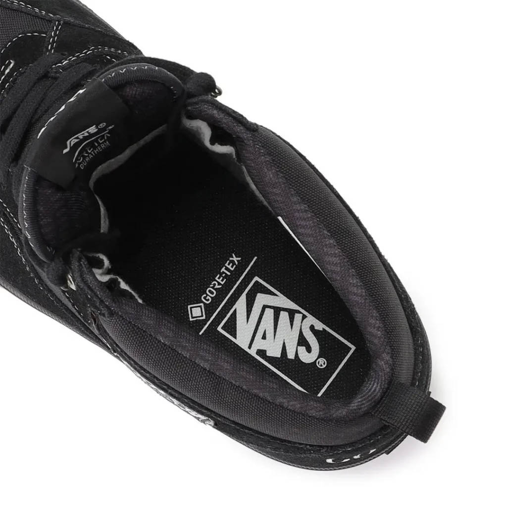 Close-up of a black Vans shoe showing its padded interior, Gore-Tex label, white stitching, and heel pull tab against white