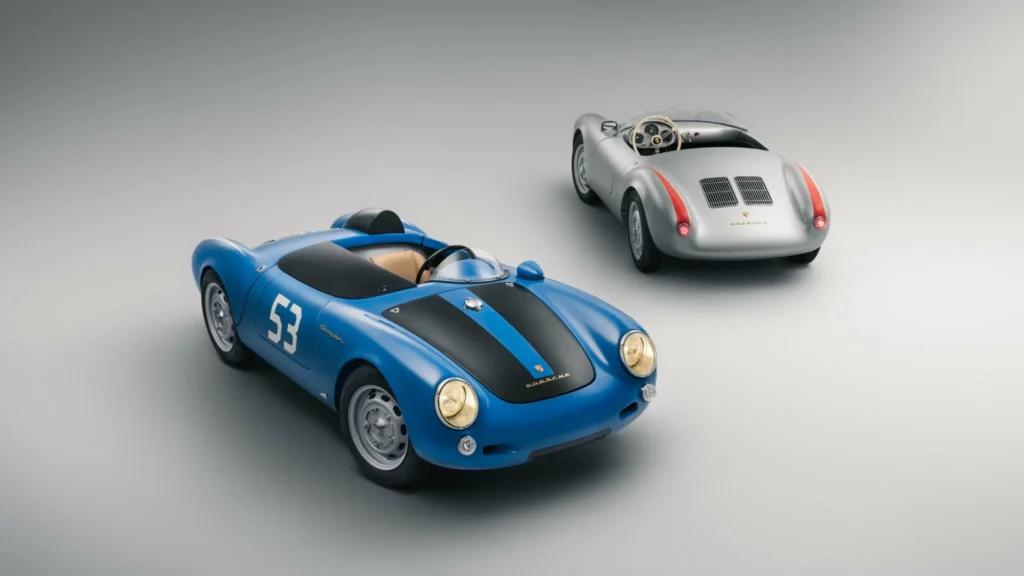 Blue Porsche 550-style race car with black hood stripes and number 53 beside a silver version in a studio setting