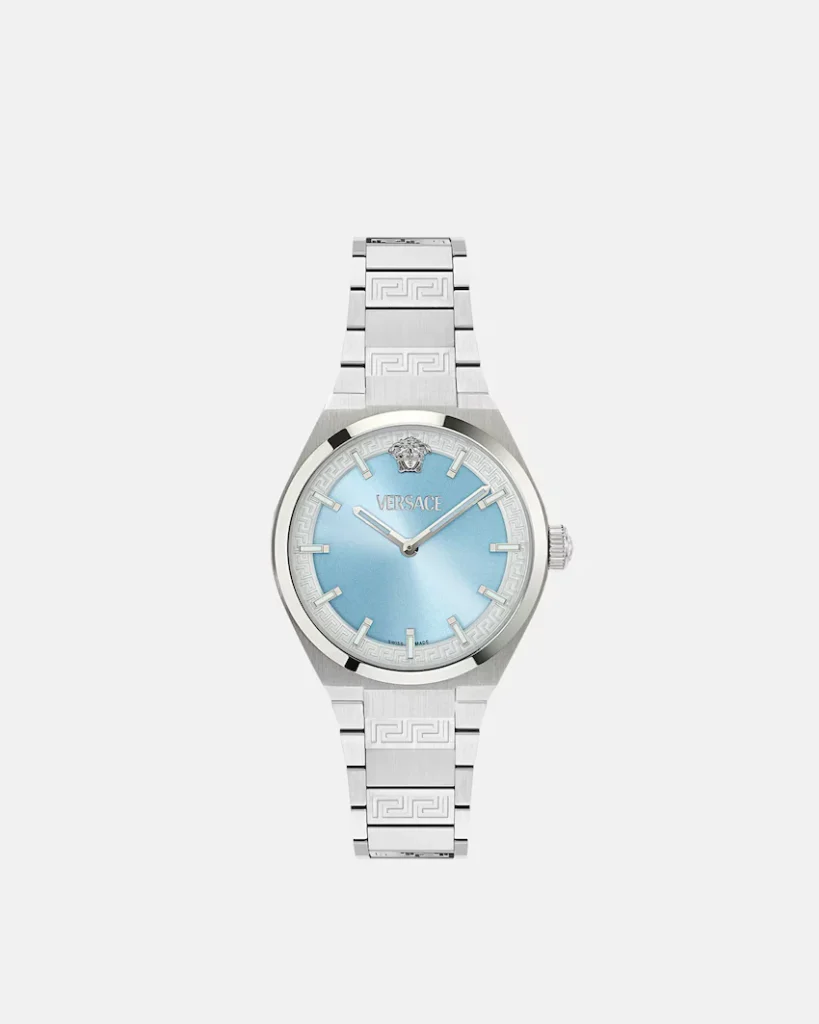 Silver Versace watch with a light blue dial, Greek key bezel and bracelet, and Medusa emblem on white background