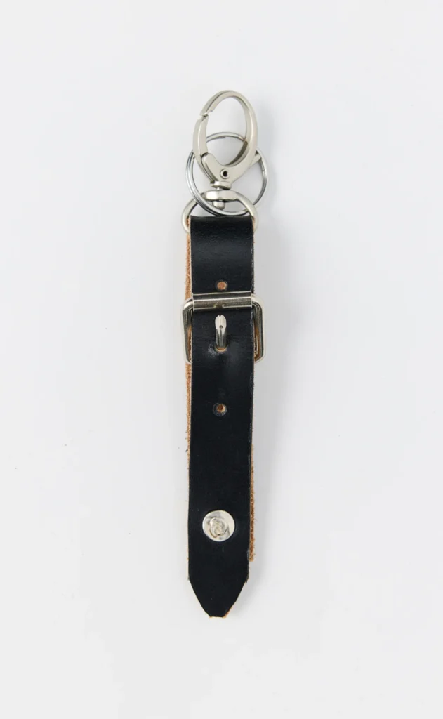 Black leather keychain with silver-tone rings, clasp, buckle, and rivets on a white background