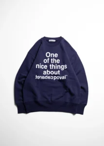 Navy crewneck sweatshirt with white text reading “One of the nice things about” and mirrored brand lettering, laid flat on