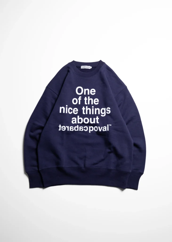 Navy crewneck sweatshirt with white text reading “One of the nice things about” and mirrored brand lettering, laid flat on