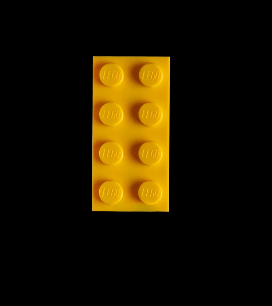 Yellow LEGO brick with eight studs, centered against a black background