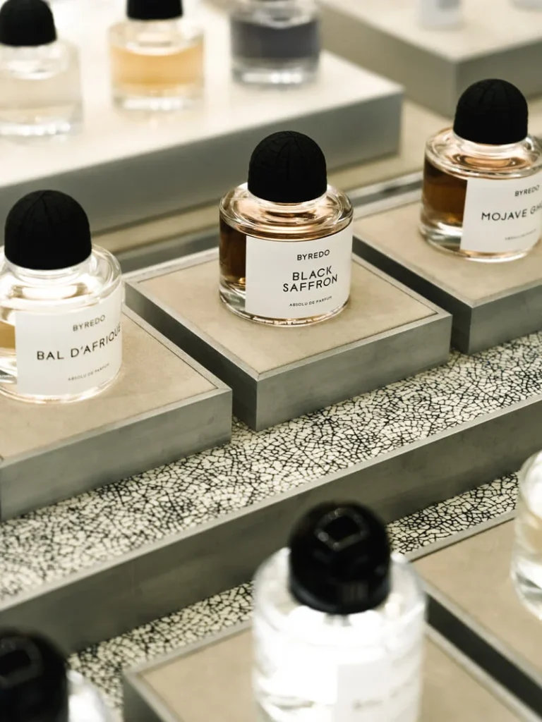 Perfume bottles displayed on tiered shelves, including labels reading Bal d’Afrique, Black Saffron, and Mojave Ghost