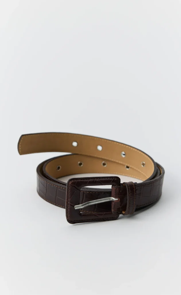 Dark brown crocodile-textured leather belt coiled on a white background, with a rectangular buckle and silver prong