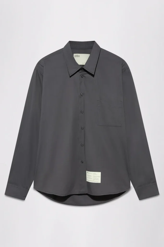 Charcoal long-sleeve button-up shirt with pointed collar, chest pocket and curved hem on a light background