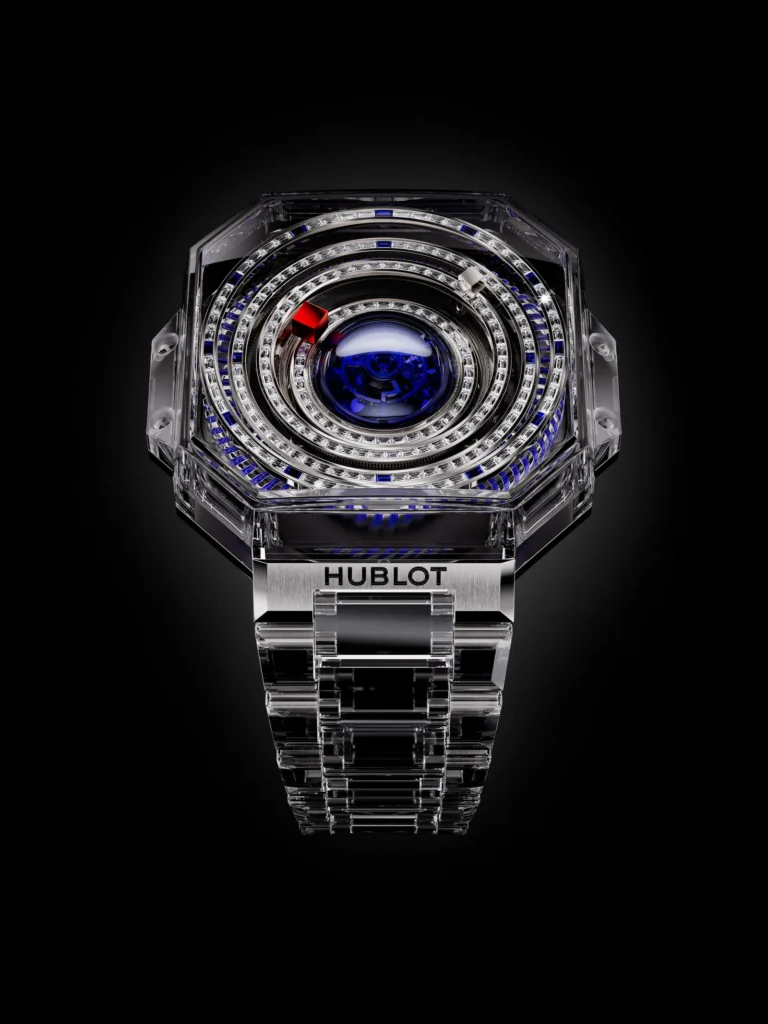 Hublot wristwatch with a transparent case, concentric jeweled dials, blue accents and metal bracelet on black background