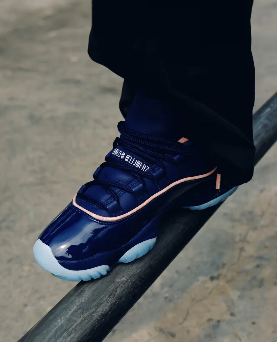Navy blue shoe with pink accents resting on a black metal rail, worn with black pants