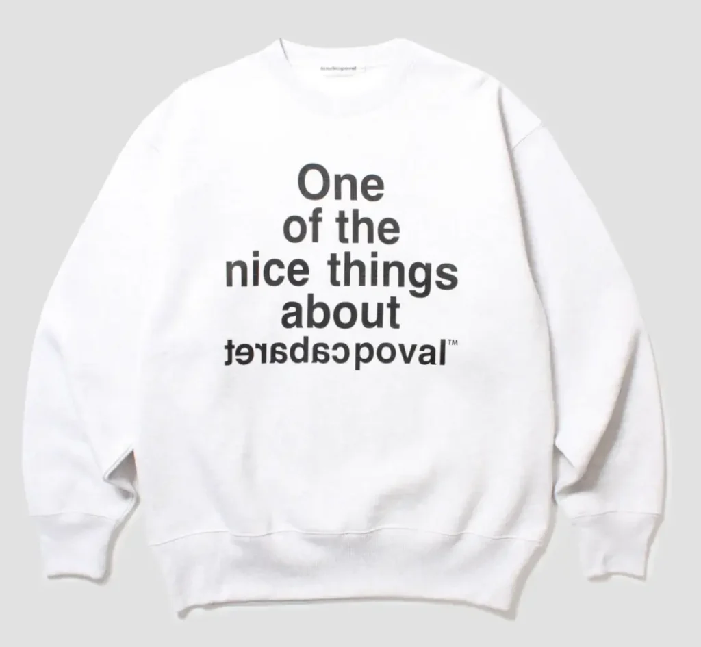 White sweatshirt with black text reading “One of the nice things about” above mirrored “leavepoverty,” laid flat on gray